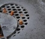 Detailed view of cigarette butts in a metal ashtray with perforated design, depicting usage and waste.