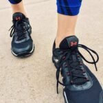 Close-up view of a person wearing black athletic sneakers on pavement, highlighting fitness and exercise.