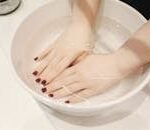 Luxurious hand spa treatment with elegant manicured nails submerged in a soothing soak.