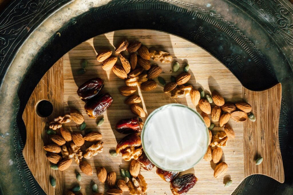 Flat lay of almonds, dates, and milk for iftar on a wooden board.