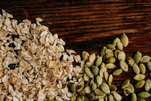 A detailed view of oats and pumpkin seeds arranged on a rustic wooden table.