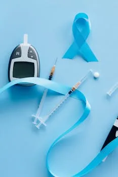 Flat lay of a glucose meter, syringe, and blue ribbon symbolizing diabetes awareness.