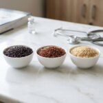 Three ceramic bowls containing Karuppu Kavuni black rice, Mappillai Samba red rice, and Aged Brown Basmati rice on a doctor's desk